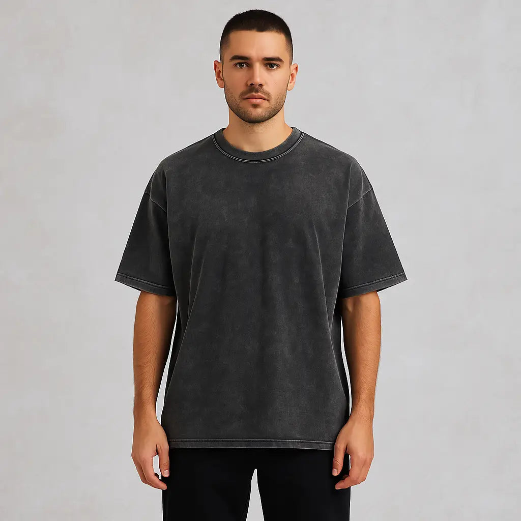 Man wearing a full-length drop shoulder charcoal acid wash t-shirt and black pants, showcasing the modern revival of vintage-inspired menswear.